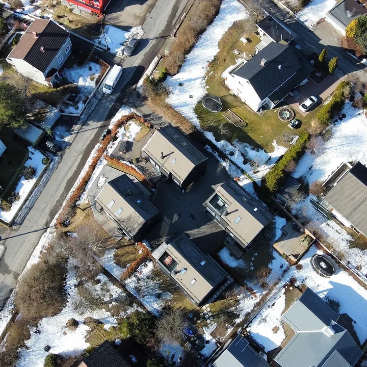 Dronebilde av et boligområde med hus og hager, tatt rett ovenfra en vinterdag