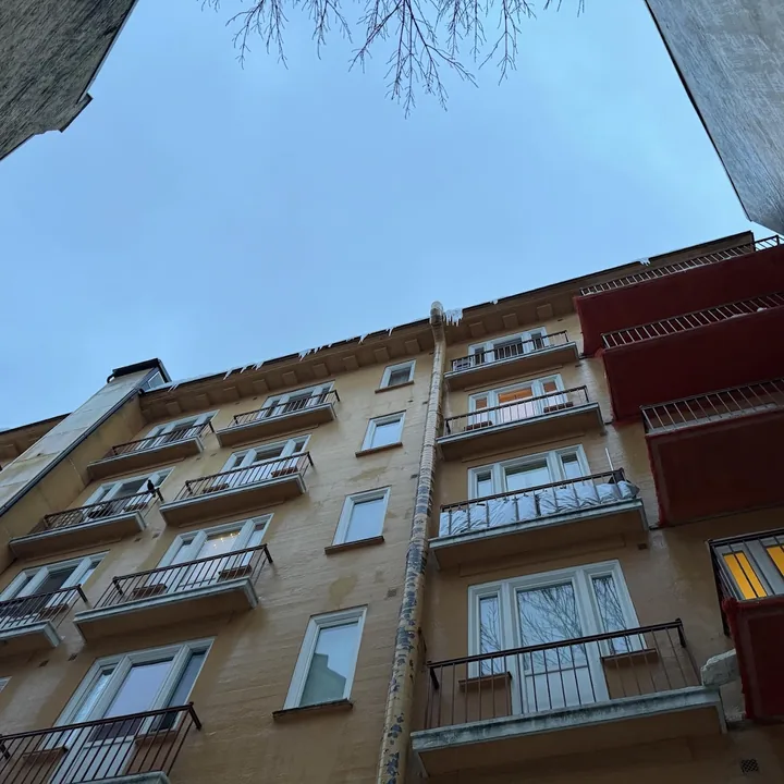 Fasaden på en bygård med balkonger, sett nedenfra